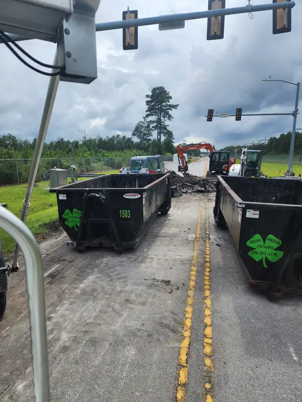 Two Irish Greens containers on a road project next to excavators